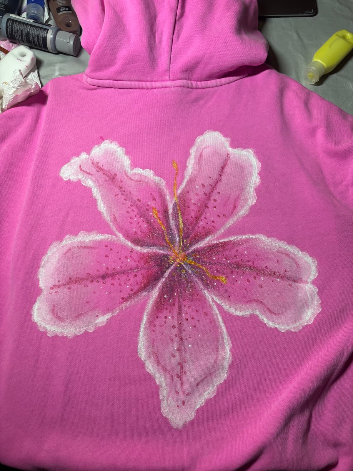 Hand-painted pink lily design, back view, on a custom sweatshirt by Madeleine MacNutt