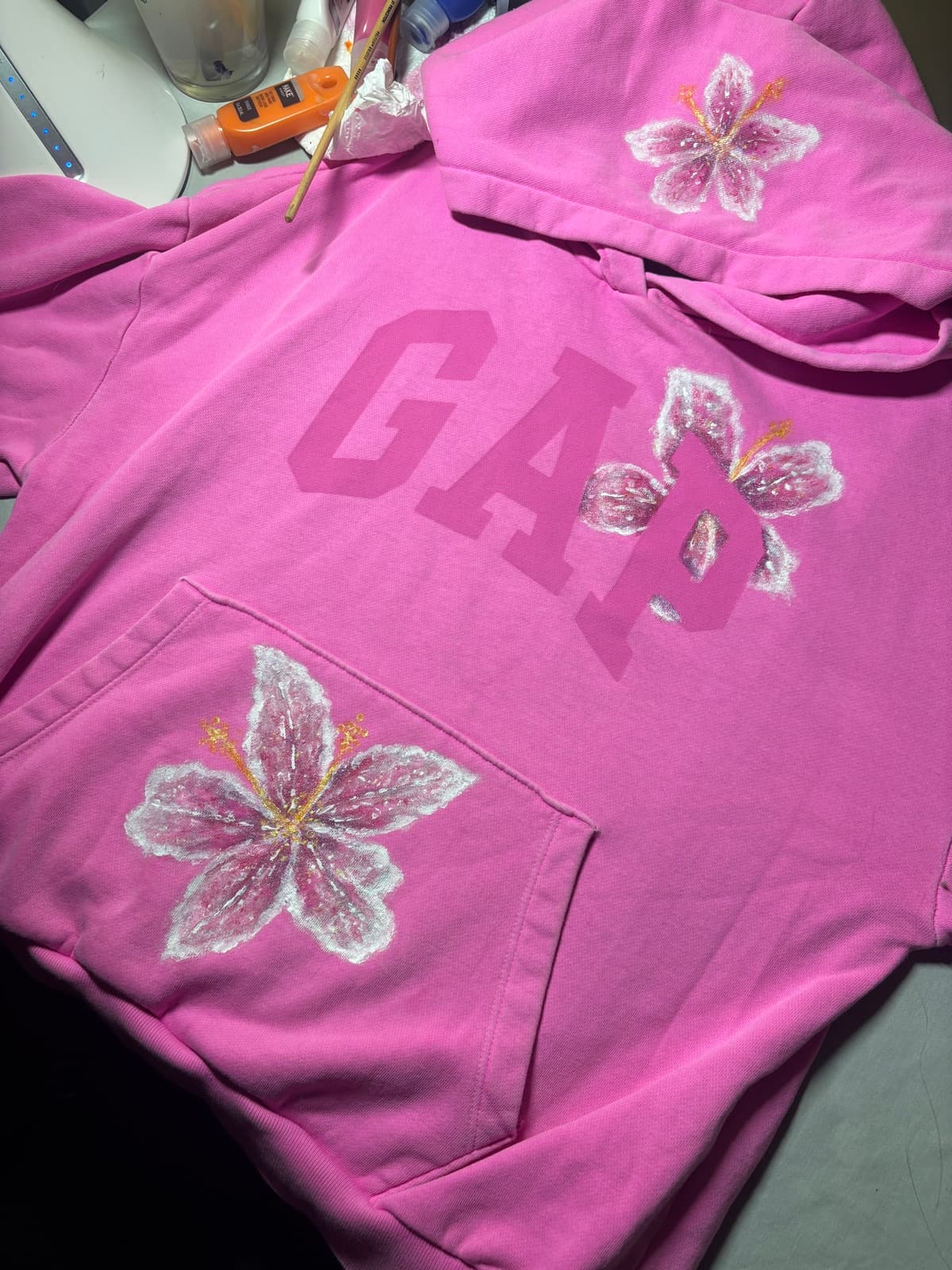Hand-painted pink lily design, front view, on a custom sweatshirt by Madeleine MacNutt